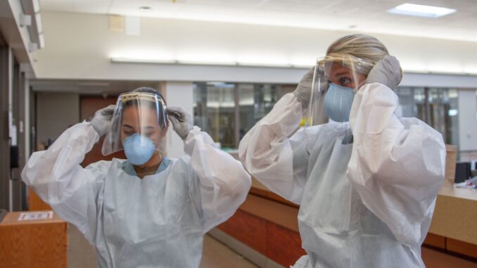 Hospitalman Angela Mello, a general duty corpsman assigned to Naval Medical Center San Diego (NMCSD) (left), and Ens. Kaitlyn Leibing, a staff nurse assigned to one of NMCSD’s internal medicine wards (right), don 3D-printed face shields, donated to the hospital by Southwest Regional Maintenance Center